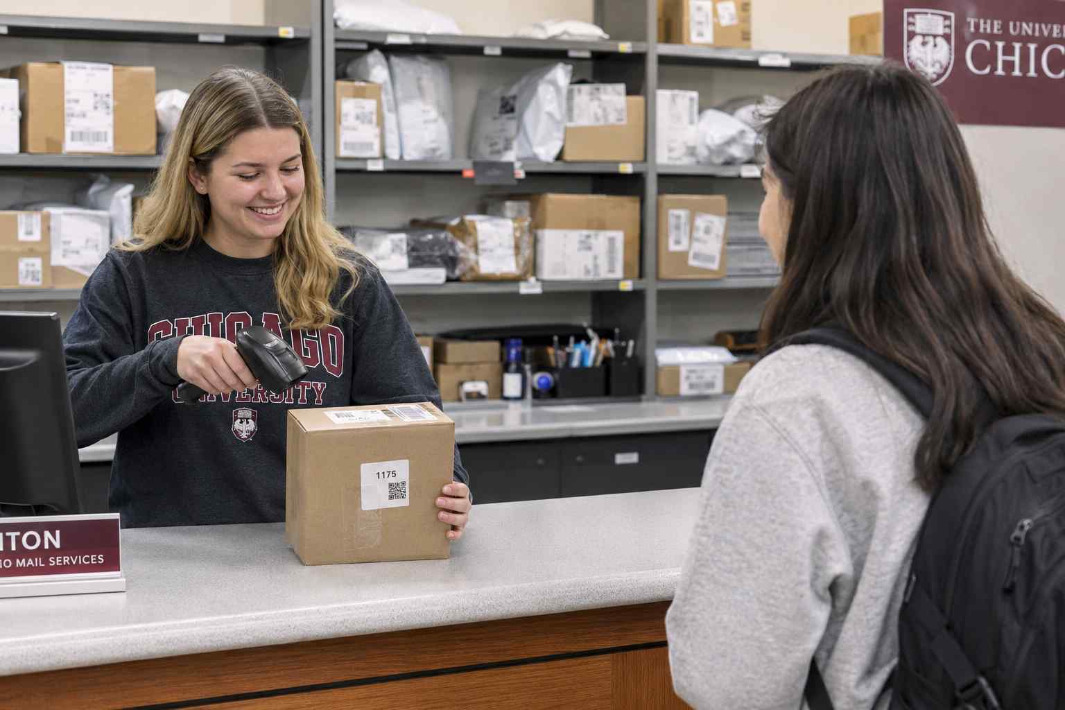 University mailroom staff scanning a QR code on a package at a pickup counter