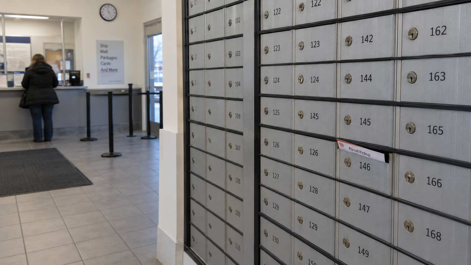 Wall of numbered P.O. boxes inside a post office lobby with a parcel pickup slip visible